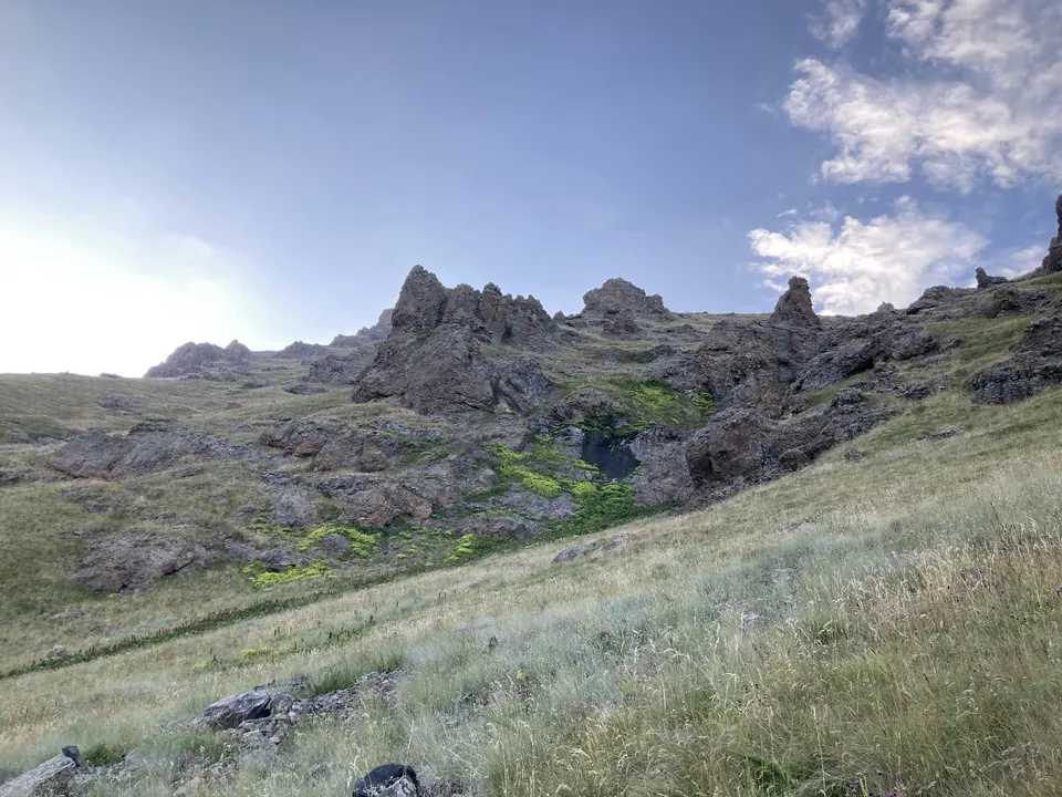 Grassy slopes and rocky crags on the descent from Mount Aragats