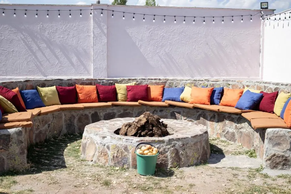 Stone fire pit ringed with colourful cushions in the garden