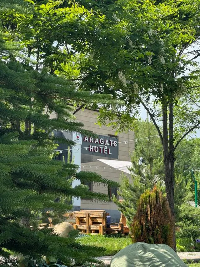 The hotel sign seen through the trees of the garden