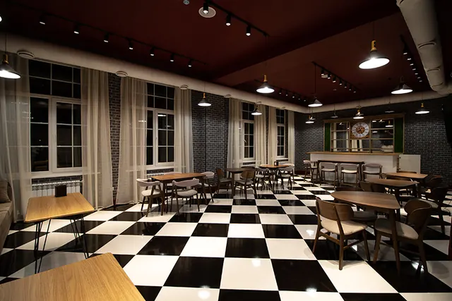 The hotel restaurant with checkerboard floor, wooden tables and pendant lights